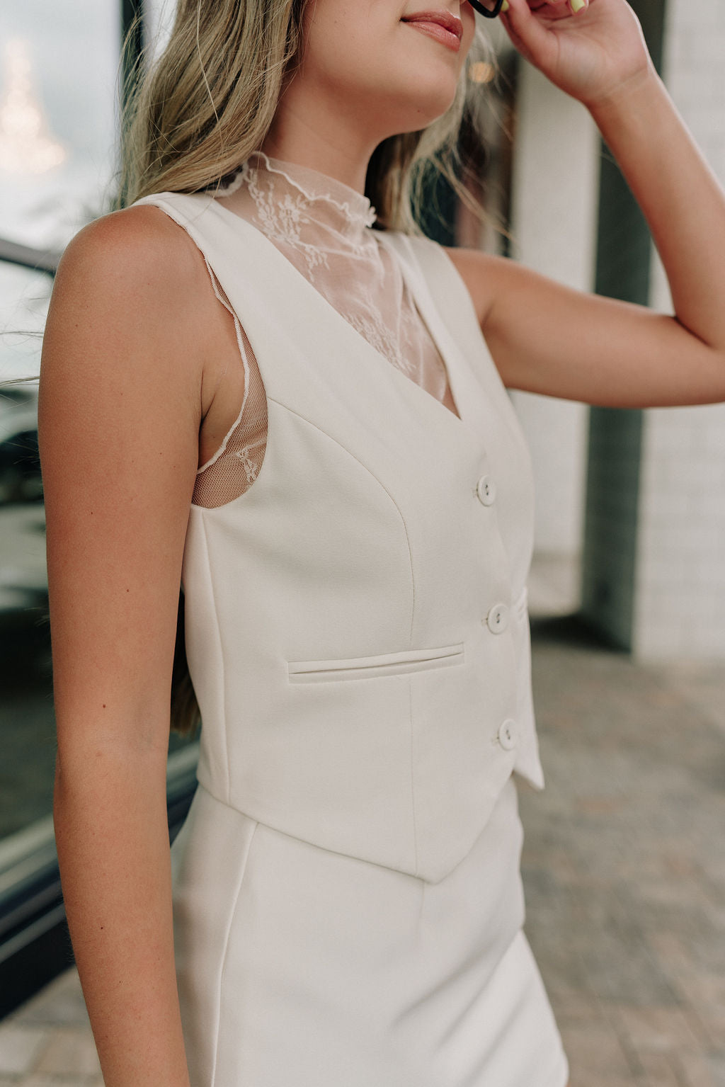 side view of female model wearing the Isabella Cream Button-Up Vest which features Cream Lightweight Fabric, Cropped Waist, Monochrome Button Up, V-Neckline and Sleeveless