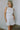 front view of female model wearing the Melissa White Satin Bow Mini Dress which features White Satin Fabric, White Lining, Mini Length, Round Neckline, Sleeveless, Side Monochrome Zipper with Hook Closure and Bow Detail