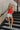 Full body front view of Kelly Red Ruffle Tank that has linen tie details and ruffle details throughout, zipper on back.
