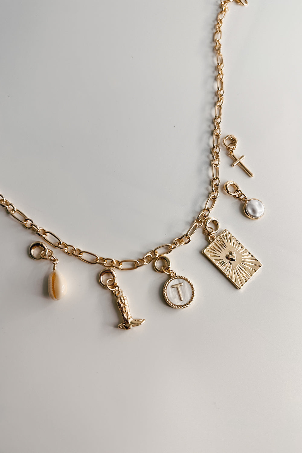 Image shows the bottom of the Kennedy Gold Chain Link Necklace against a white background. Necklace has gold circle and oval links. Shown with 6 assorted charms added.