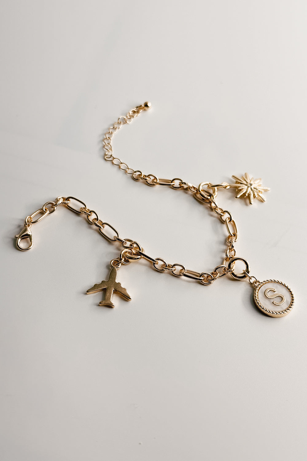 Image shows the Reagan Gold Chain Link Bracelet against a white background. Bracelet has gold circle and oval links. Shown with 3 assorted charms attached.