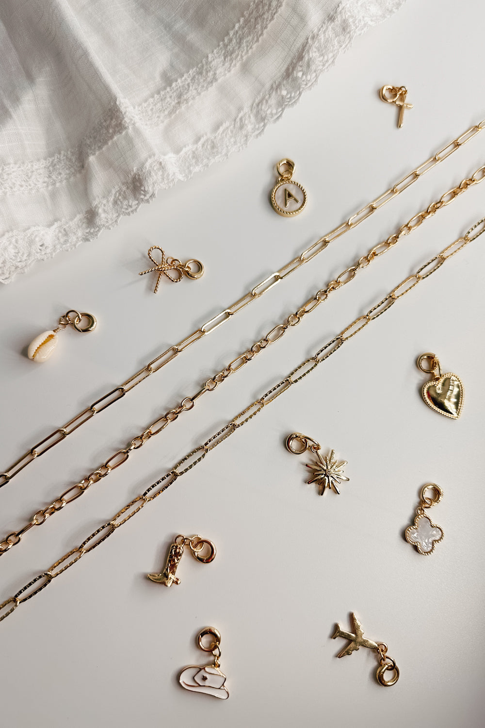 Image shows 3 chain necklaces laid out with assorted charms on each side. Shown against a white background