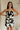 front view of female model wearing the Lila Black & Cream Tie Straps Romper which features Black and White Geometric Pattern, White Shorts Lining, Two Side Pockets, Ruffle Upper, Square Neckline and Tie Straps