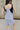 Close up back view of model wearing the Ariana Grey Romper. This is a grey romper, sleeveless, with pockets.