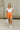Full body view of model wearing the Kendra Square Neck Padded Bodysuit in white. This is a bodysuit with a square neckline, thong button closure, and short sleeves., comes in either black or white.