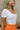 Close up view of model wearing the Kendra Square Neck Padded Bodysuit in white. This is a bodysuit with a square neckline, thong button closure, and short sleeves., comes in either black or white.