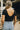 Close up of back of model wearing the Kendra Square Neck Padded Bodysuit in black. This is a bodysuit with a square neckline, thong button closure, and short sleeves., comes in either black or white.