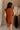 Back view of female model wearing the Monica Rust Mock Neck Sweater Dress that has rust colored knit fabric, a mock neck, and mini length hem.