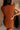 Close-up back view of female model wearing the Monica Rust Mock Neck Sweater Dress that has rust colored knit fabric, a mock neck, and mini length hem.