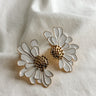 Flat lay view of the Chloe White & Gold Flower Stud Earring which features  oversized white flower studs with gold details