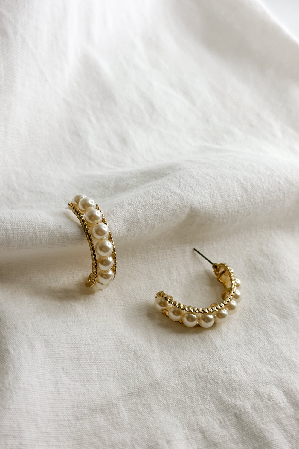 Flat lay view of the Elisa Gold Rope & Pearl Hoop Earring which features gold rope hoops with pearls