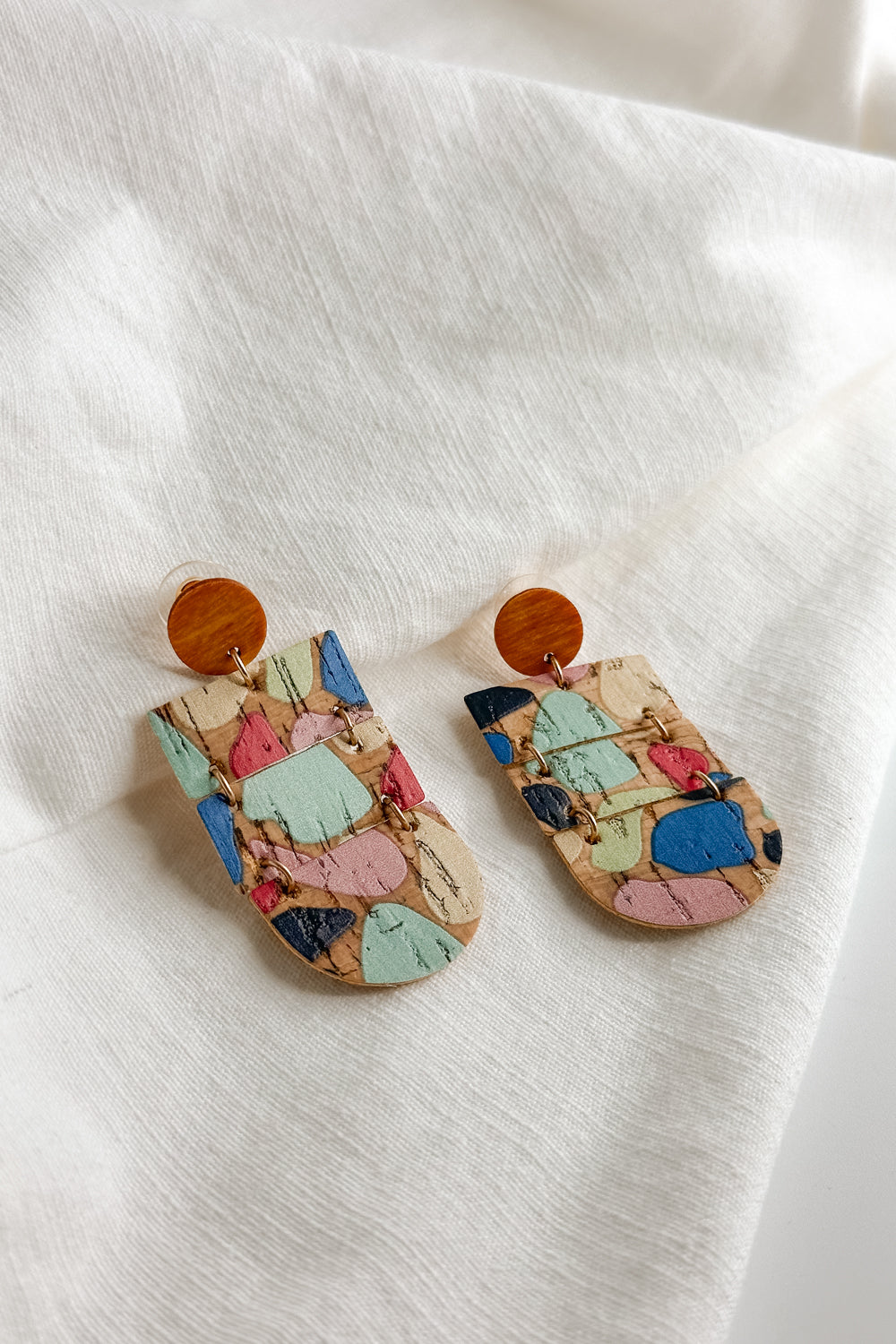 Flat lay view of the Wrenly Cork Multi Dangle Earring which features cork dangle earrings with multi color spots design