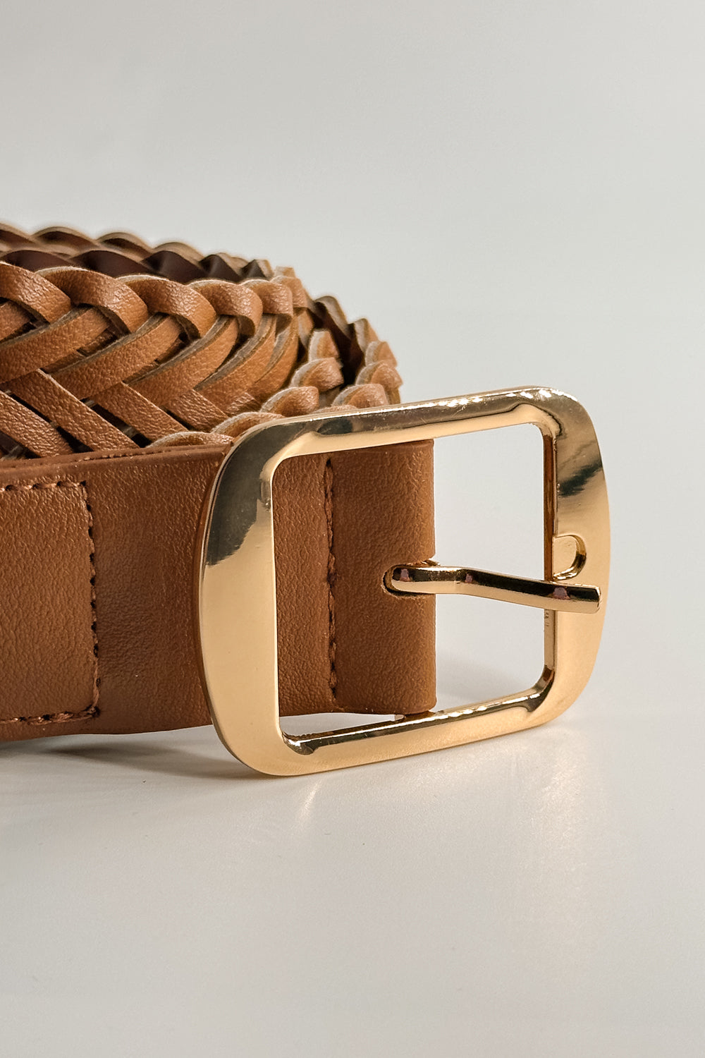 Close up view of the Everly Braided Adjustable Belt in Brown which features brown Leather Fabric, Braided Details, Gold Adjustable Buckle