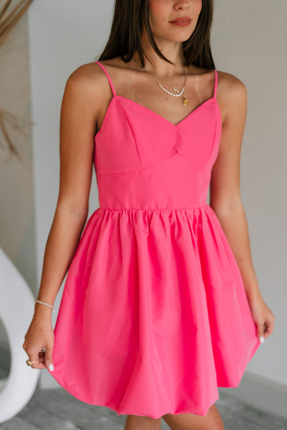Close up view of female model wearing the Camila Sleeveless Bubble Mini Dress in PInk which features Lightweight Fabric, Mini Length with Bubble Hem, Two Side Slit Pockets, Sweetheart Neckline, Adjustable Straps and Smocked Back
