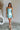 Full body view of female model wearing the Dorit Light Blue Satin Mini Dress which features Light Blue Shimmer Fabric, Mini Length, Cowl Neckline and Skinny Straps