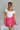 Front view of female model wearing the Gabriella Pink Ruffle Mini Skort which features Pink Lightweight Fabric, Pink Shorts Lining, Ruffle Pleated Hem Details and Side Tie Detail
