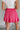 Back view of female model wearing the Gabriella Pink Ruffle Mini Skort which features Pink Lightweight Fabric, Pink Shorts Lining, Ruffle Pleated Hem Details and Side Tie Detail