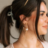 Side view of female wearing the Cora Gold Ribbed Pearl Hoop Earring which features gold ribbed open hoops with a single pearl detail