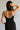 Upper body back view of model wearing the Gianna Black & White Midi Dress that has black fabric, and white straps with white neckline bow trim.