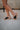 Right side view of female model wearing the B.O.C. Born Concept Sunny Wedge Sandal in Black which features Black Faux Leather Upper, Slip-On Style and Criss-Cross Strap & Toe Wrap Detail