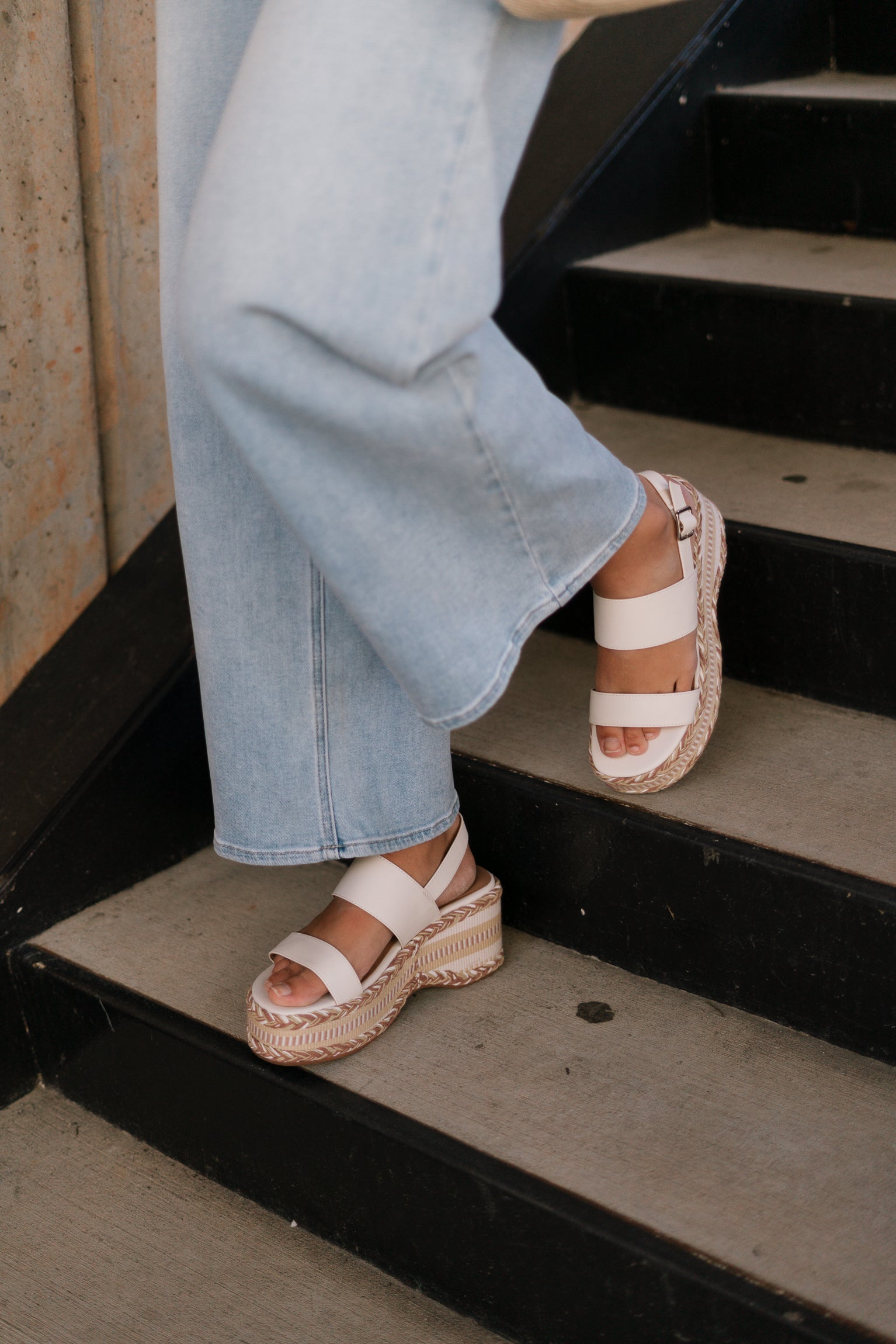 Front side view of female model wearing the Surrey Platform Sandal in Ivory which features Ivory Leather Upper Straps, Adjustable Buckle Back Strap, Memory Foam and Ivory and Tan Texture Espadrille Sole