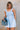 front view of female model wearing the Taylor Light Wash Denim Romper that has light wash denim fabric, straps with frayed hems, elastic waist, neckline pleating, and side pockets.