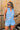 Front view of female model wearing the Georgia Belted Denim Romper in light wash, that has a button up front, collar, and belted waist.