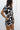 Upper body side view of female model wearing the Valerie Black & White Short Sleeve Romper that has a black and white abstract print, short sleeves, a collar, button up front, and elastic waist with tie.