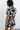Upper body back view of female model wearing the Valerie Black & White Short Sleeve Romper that has a black and white abstract print, short sleeves, a collar, button up front, and elastic waist with tie.