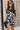 Upper body front view of female model wearing the Valerie Black & White Short Sleeve Romper that has a black and white abstract print, short sleeves, a collar, button up front, and elastic waist with tie.
