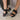 Side view of female model wearing the Kinetic Impact Slingback Heel Sandal in Black which features Black and White Leather Upper Fabric, Leather Strap, Adjustable Hook and Velcro Strap Closure,  1 1/2" Platform Sole and 2 1/12" Heel Height