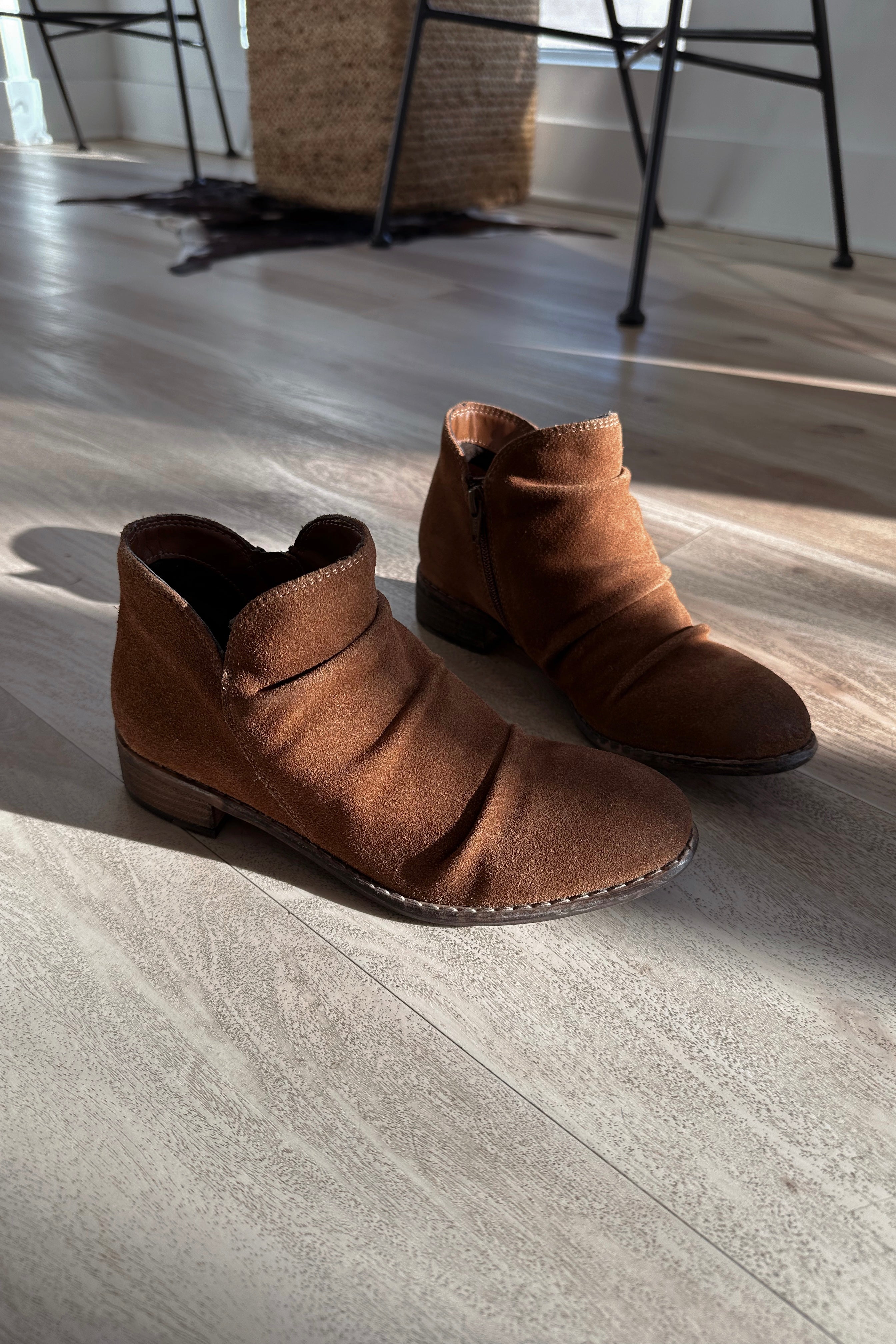 Side view of the Rose Mera Bootie in Tan Suede which features light brown suede fabric, slouched details, inside zipper closure, round toe, lightly cushioned footbed and 1.25" stack heel
