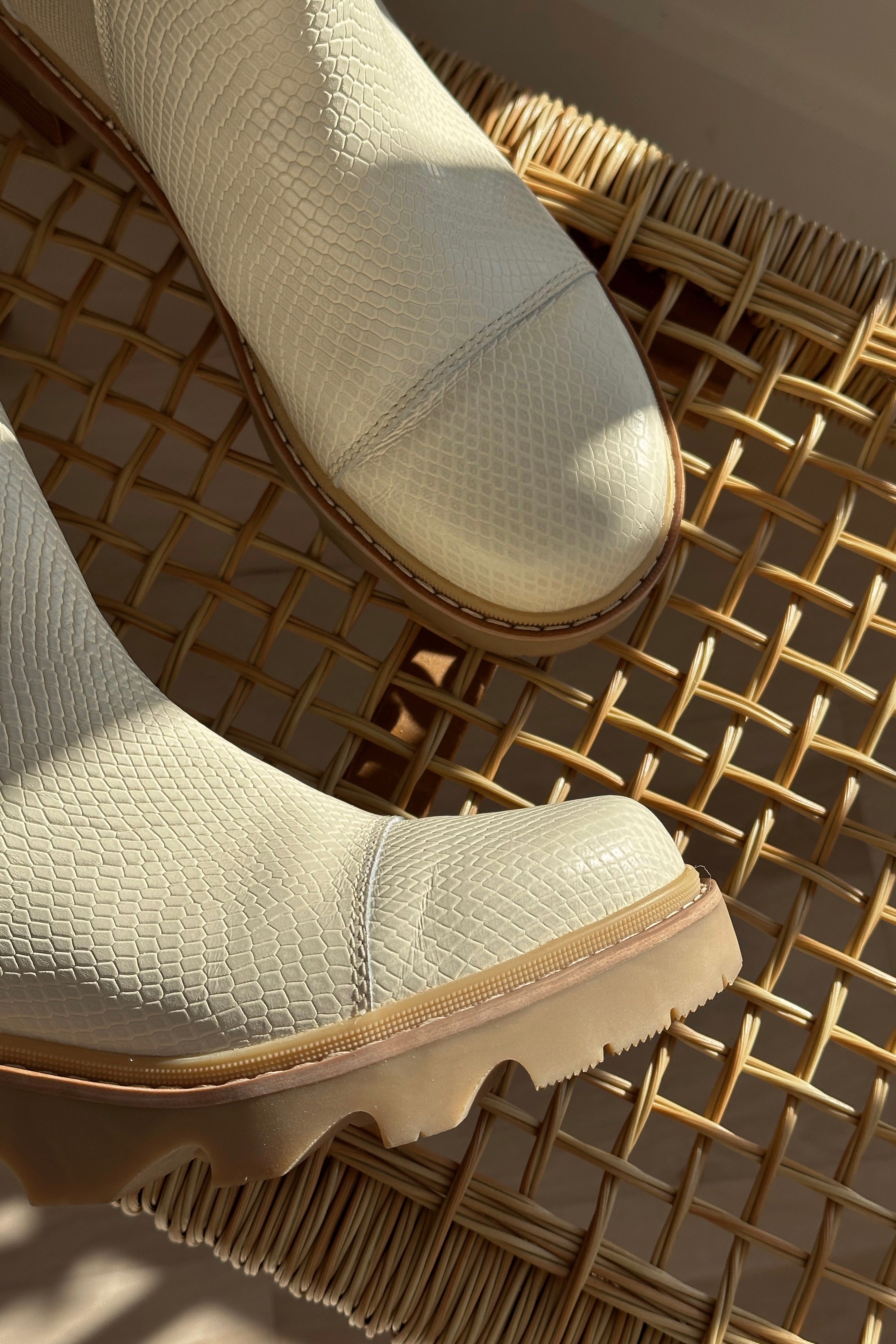 Close up view of the Joan Now Chelsea Bootie in Bleached Ceramic which features cream waterproof leather, ridged light brown sole, heel pull tab, round toe, 2 inch heel height and 3/4" platform height