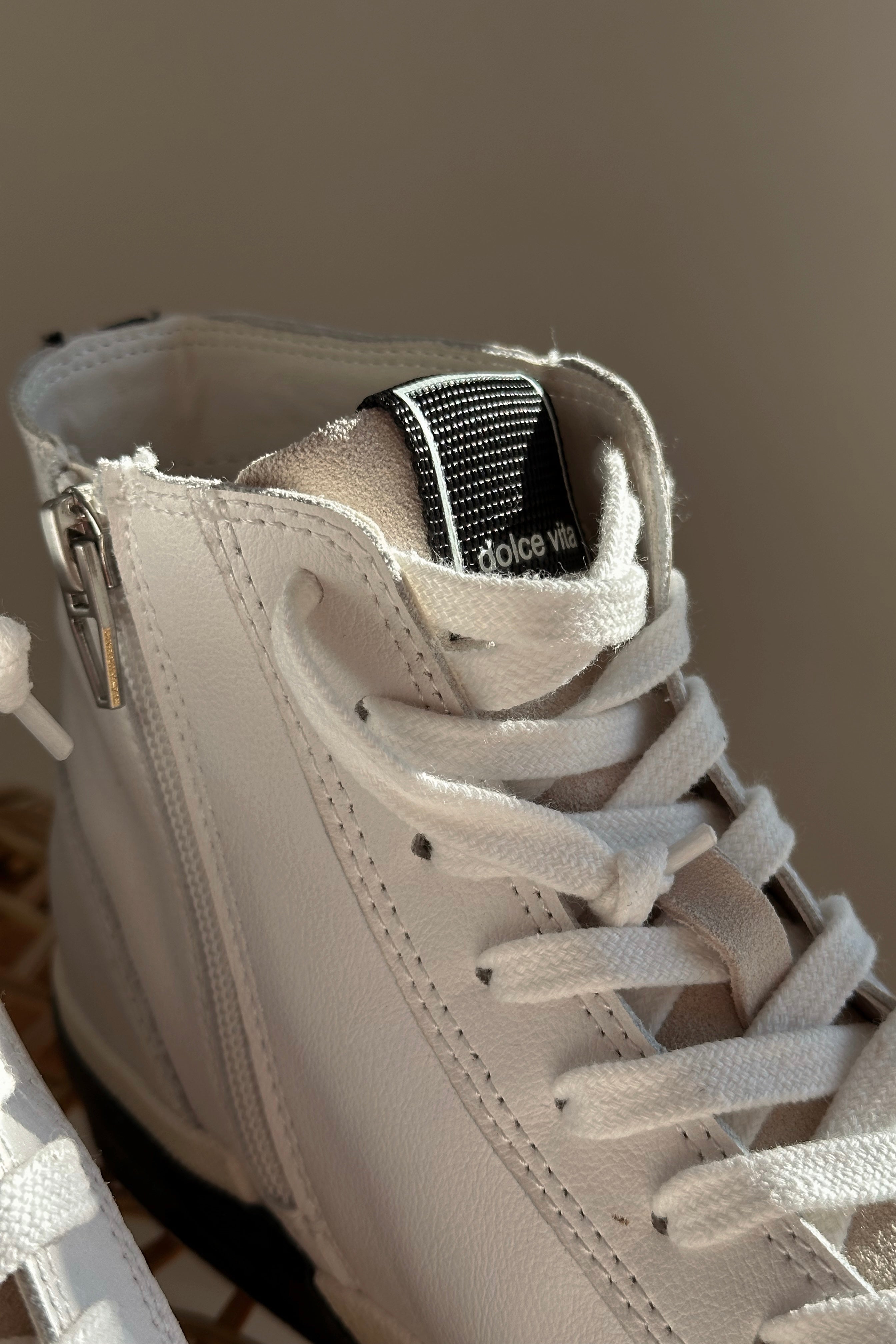 Close up view of the Zohara Sneaker in White Black Leather which features black, brown and white leather upper, off white suede upper, color-block design, high-top style, round toe, lace up details and back zipper closure