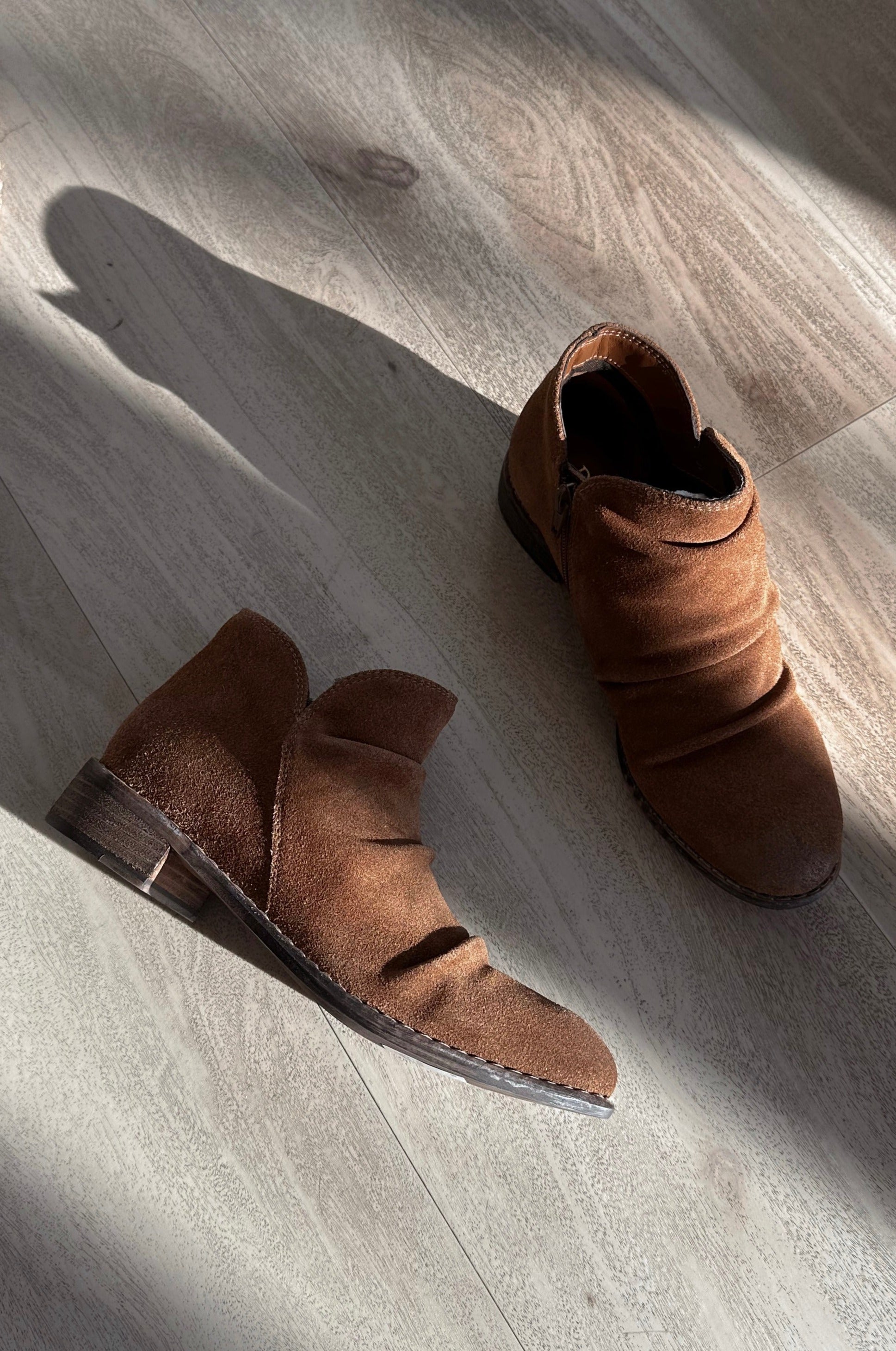 Ariel view of the Rose Mera Bootie in Tan Suede which features light brown suede fabric, slouched details, inside zipper closure, round toe, lightly cushioned footbed and 1.25" stack heel