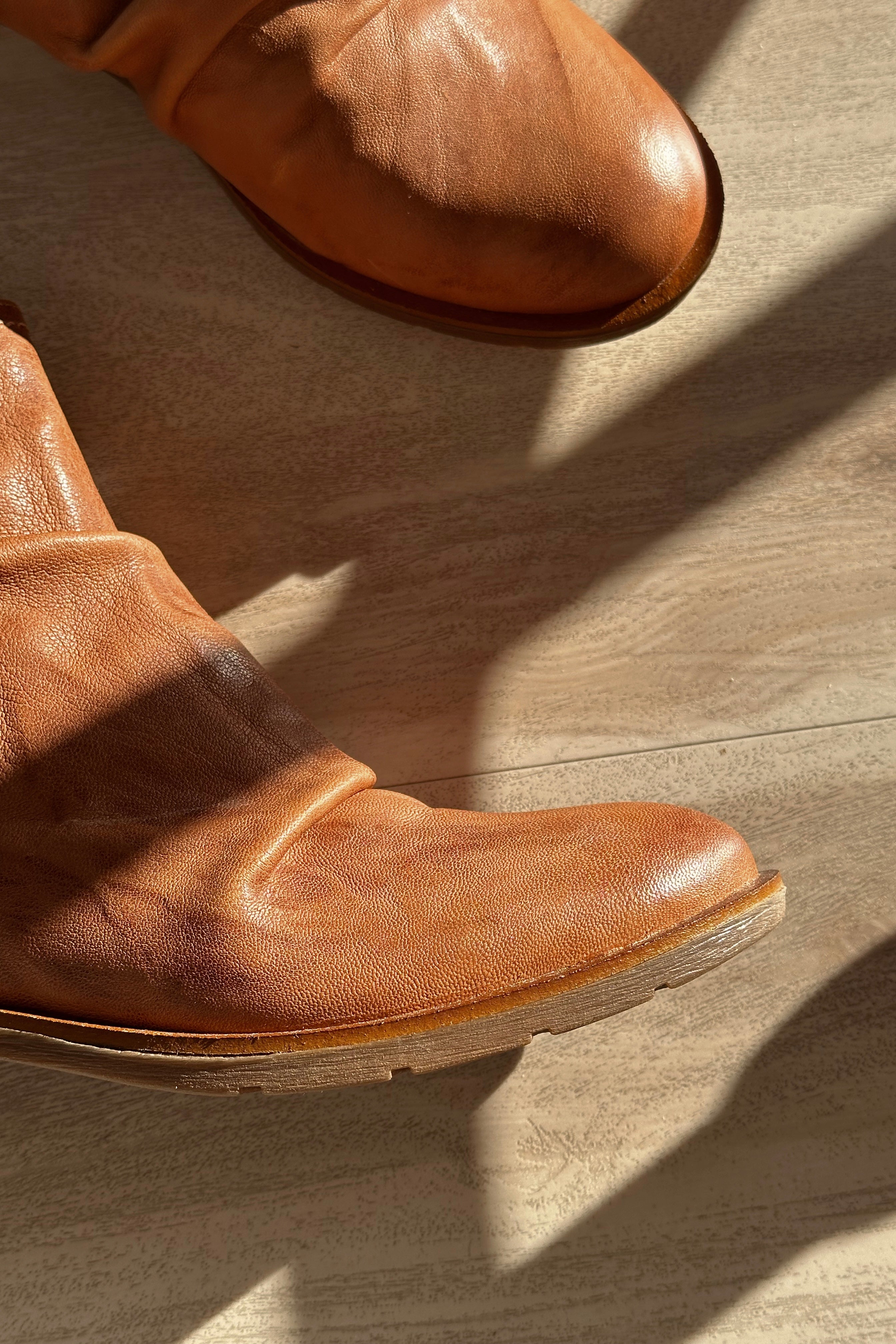 Close up view of the Beckie Boot in Luggage which features light brown leather fabric, heel tab, cushioned footbed, slouched details and heel height is 1 1/2 inches
