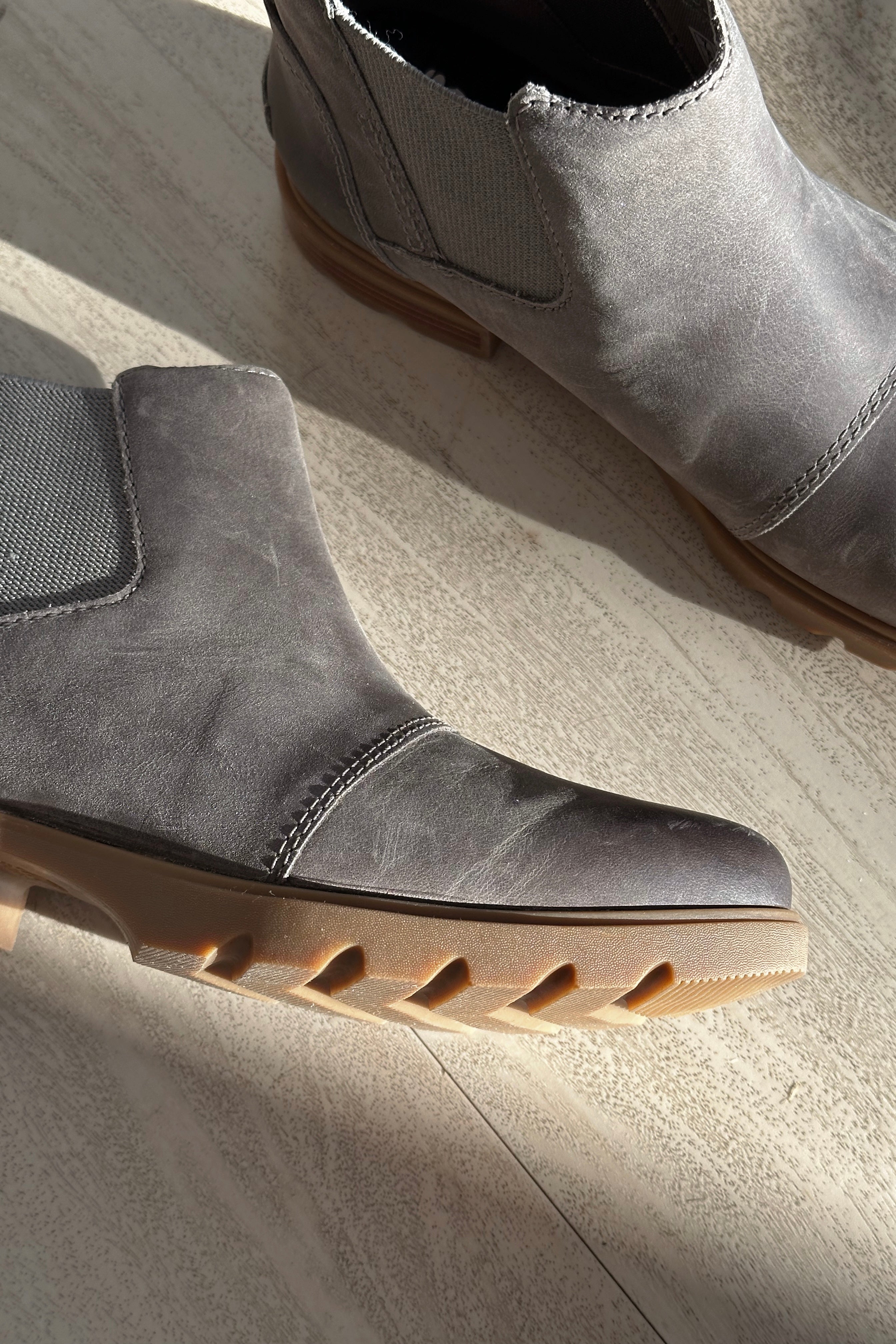 Close up view of the Emelie III Chelsea Bootie which features grey lightweight waterproof leather upper, side stretch panels, pull tabs, ridged brown sole, 1 inch heel height and 3/4 inch platform height