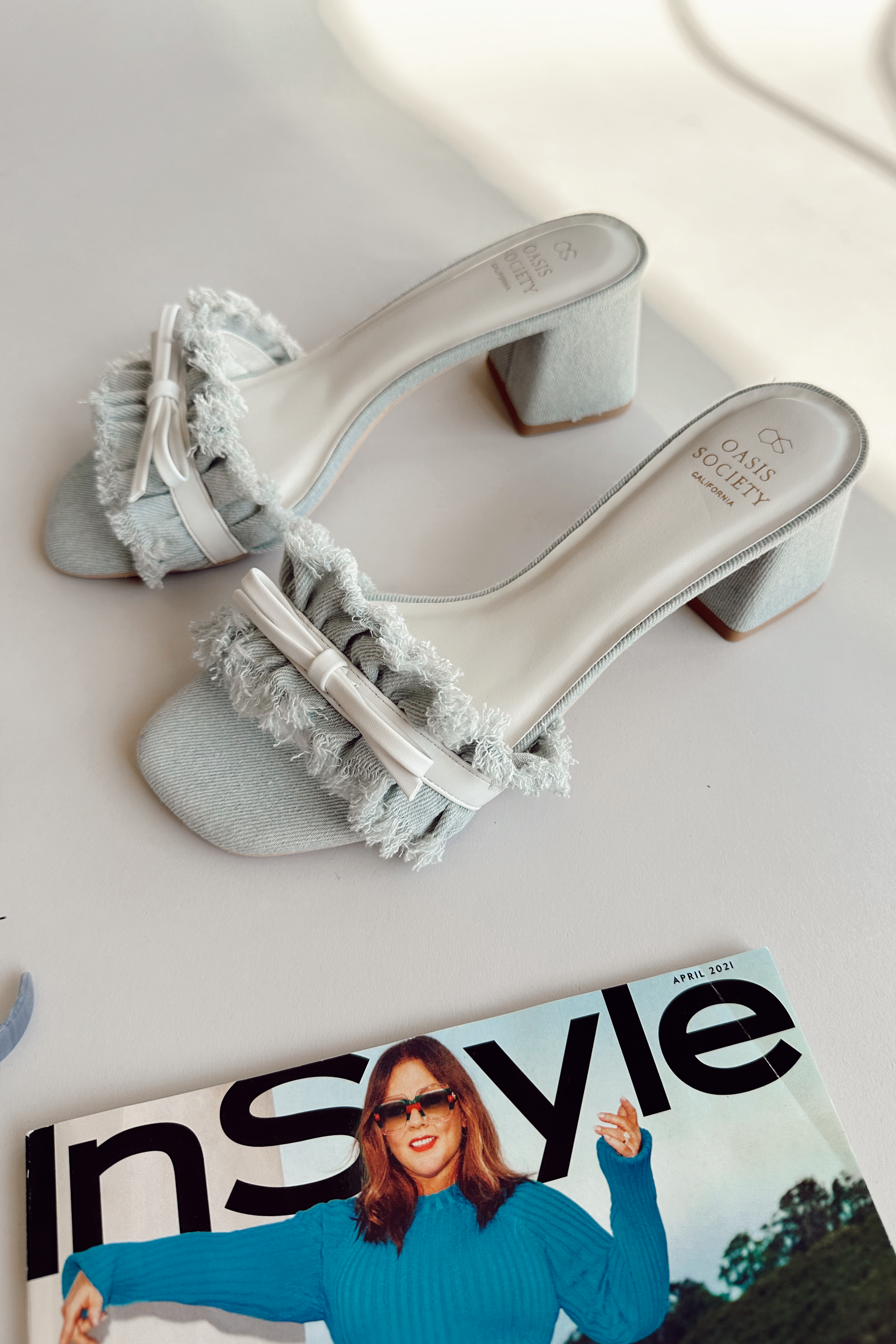 Ariel side view of the Julissa Light Denim Bow Slide Heel which features light denim fabric, slide-on style, block heel and single fray strap with white bow detail.