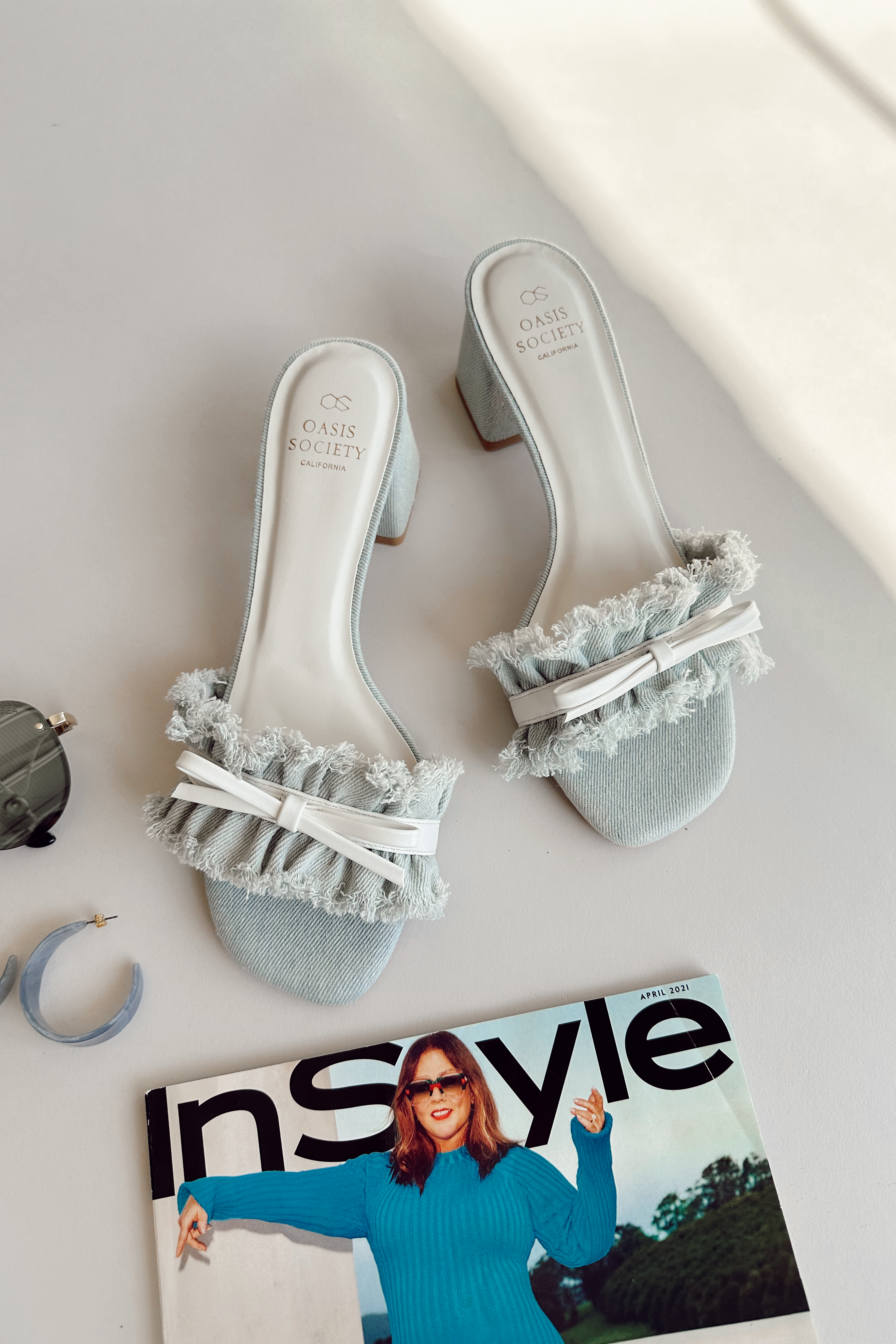 Ariel view of the Julissa Light Denim Bow Slide Heel which features light denim fabric, slide-on style, block heel and single fray strap with white bow detail.