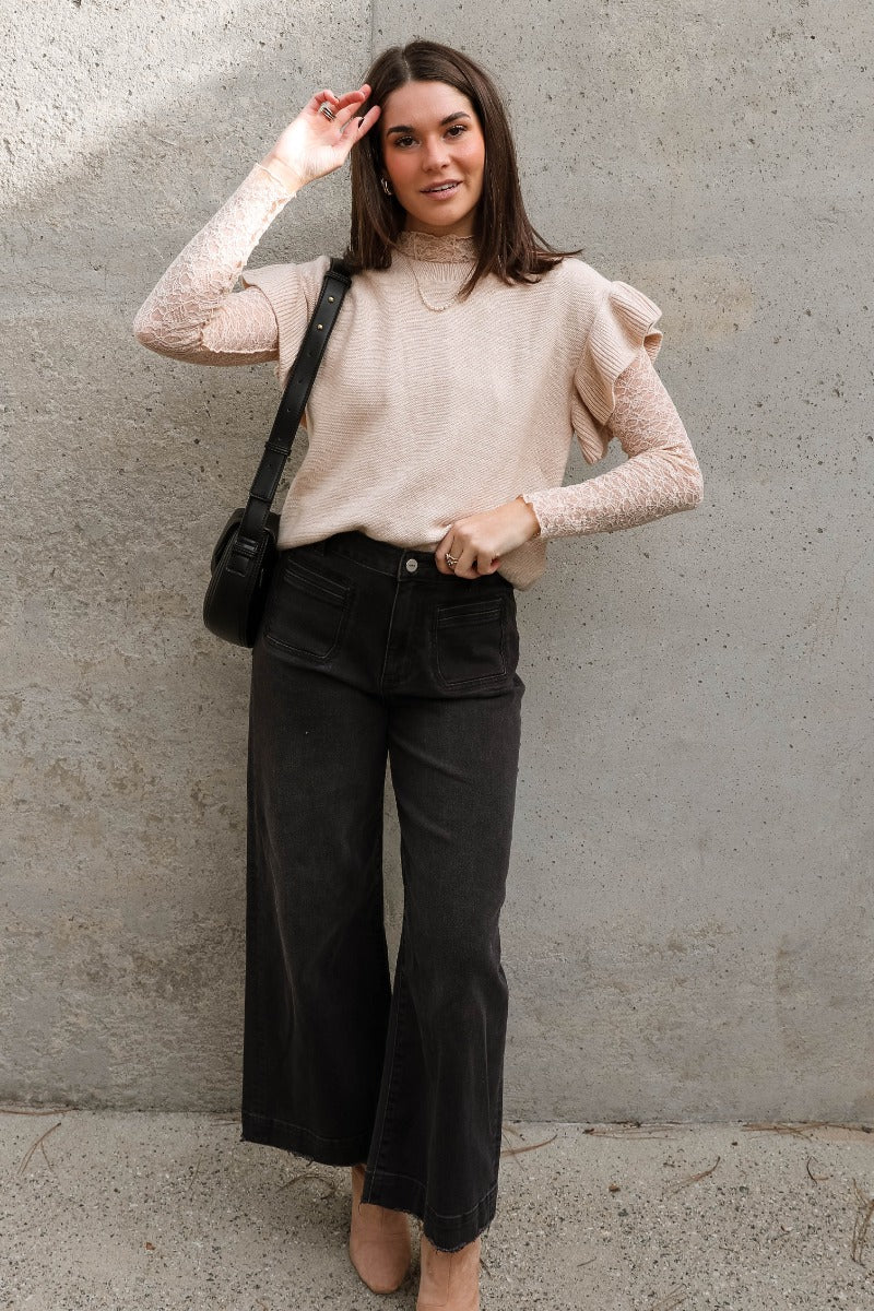 Full body view of model wearing the Sierra Beige Knit Ruffle Sweater which features beige knit fabric, a thick hem, a round neckline, and short sleeves with ruffle trim.
