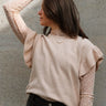 Front view of model wearing the Sierra Beige Knit Ruffle Sweater which features beige knit fabric, a thick hem, a round neckline, and short sleeves with ruffle trim.
