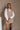 front view of model wearing the Thea Two-in-One Sweater Vest Dress that has a beige knit mini-length sweater dress with a ribbed hem, a v-neckline, and an attached white faux oxford top.