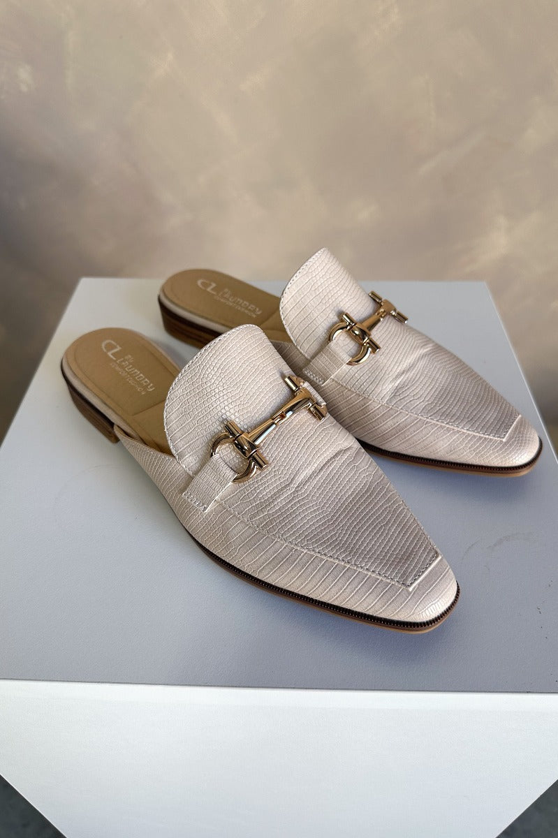 Front right angle view of the Score Lizard Cream Gold Buckle Mule which features cream snakeskin faux-leather, a gold buckle detail, backless slide entry, and a 1" heel.
