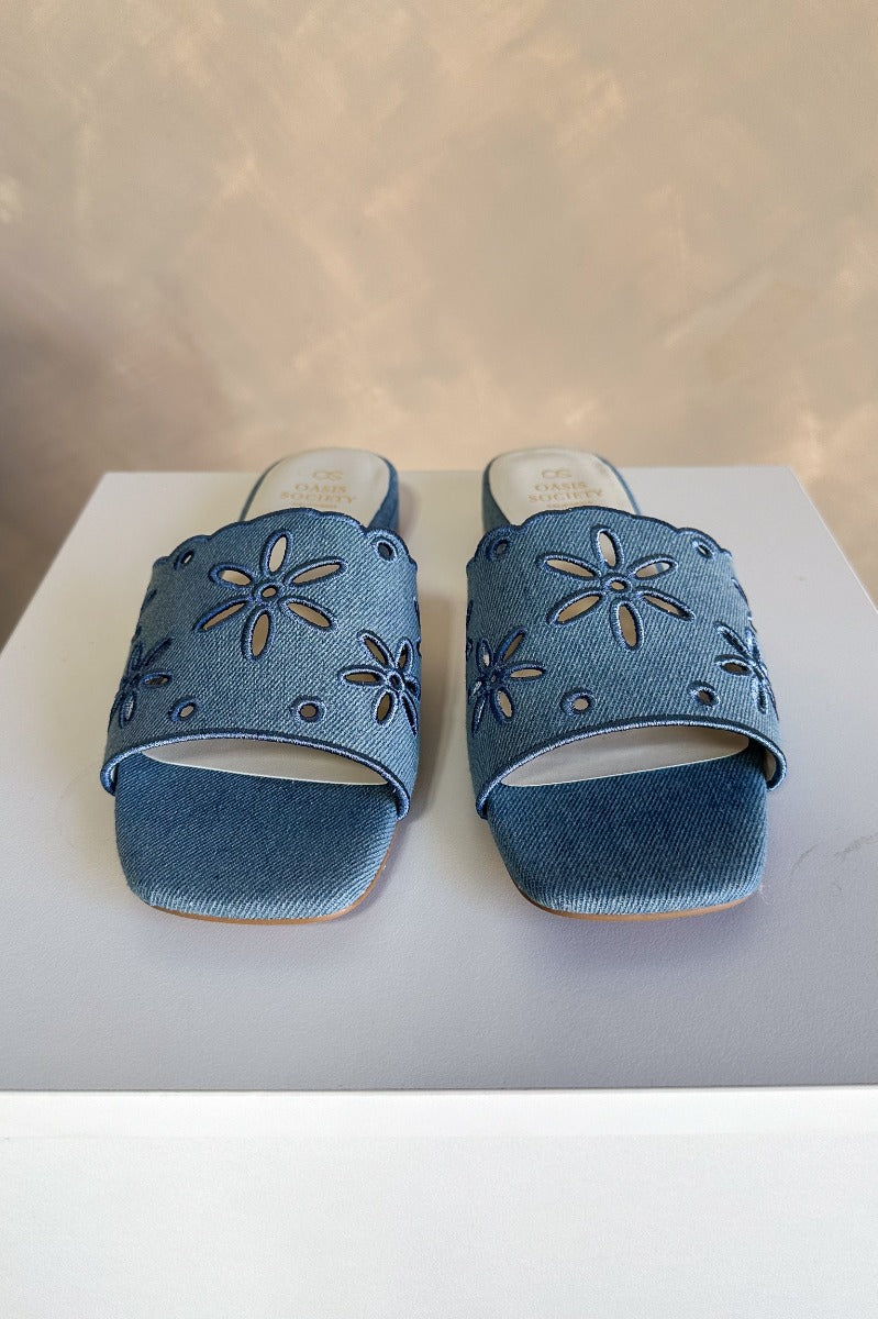 Front view of the Manila Denim Eyelet Flower Heel Sandal which features blue denim fabric with eyelet flower details, square toes, backless slide entry, and 1" heels.