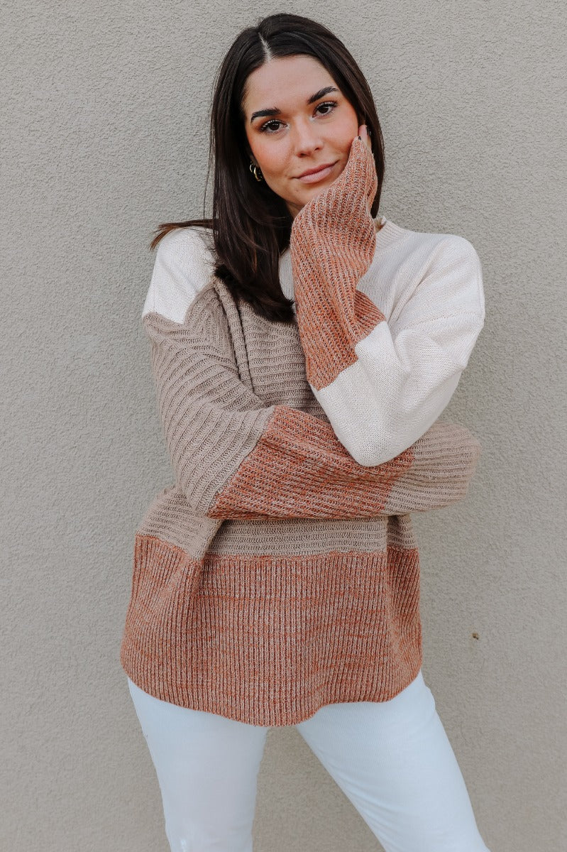 Front view of model wearing the Layla Taupe Multi Long Sleeve Sweater which features taupe, cream and rust knit fabric, ribbed details, a round neckline and long sleeves.
