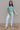 Full body view of model wearing the Celeste Sage Multi Long Sleeve Sweater which features sage, light blue and cream cable knit fabric, a colorblock pattern, a cropped waist, ribbed trim, a round neckline, dropped shoulders, and long balloon sleeves with 