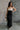 Full body front view of model wearing the Kaliyah Black & Cream Satin Midi Dress that has black, taupe and cream satin fabric, midi length, slits, a colorblock detail, a scoop neck, tie straps, and an open back.