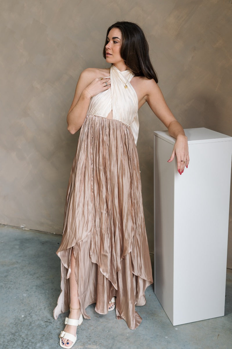 Full body front view of model wearing the Rosalia Cream & Taupe Layered Satin Midi Dress that has cream and taupe satin, midi length, layered pleated details, a halter neck and open back.