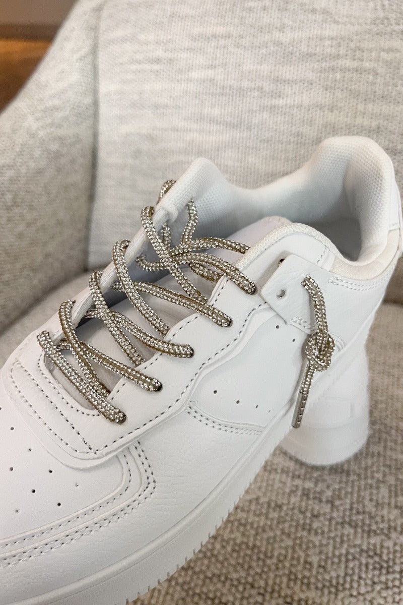 Close top view of the Eden Sneakers that have white faux-leather uppers, platform soles, and rhinestone laces.