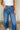Close up view of model wearing the Ceros: Florence Medium Wash Wide Leg Jeans which features medium blue denim fabric, a front zipper with a button closure, belt loops, a super high-rise waist, two front pockets, two back pockets, and wide cropped legs wi